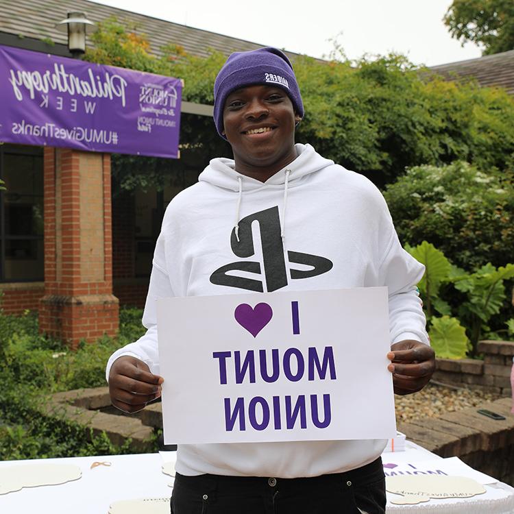 Mount Union student holding "I heart Mount Union" sign on campus.